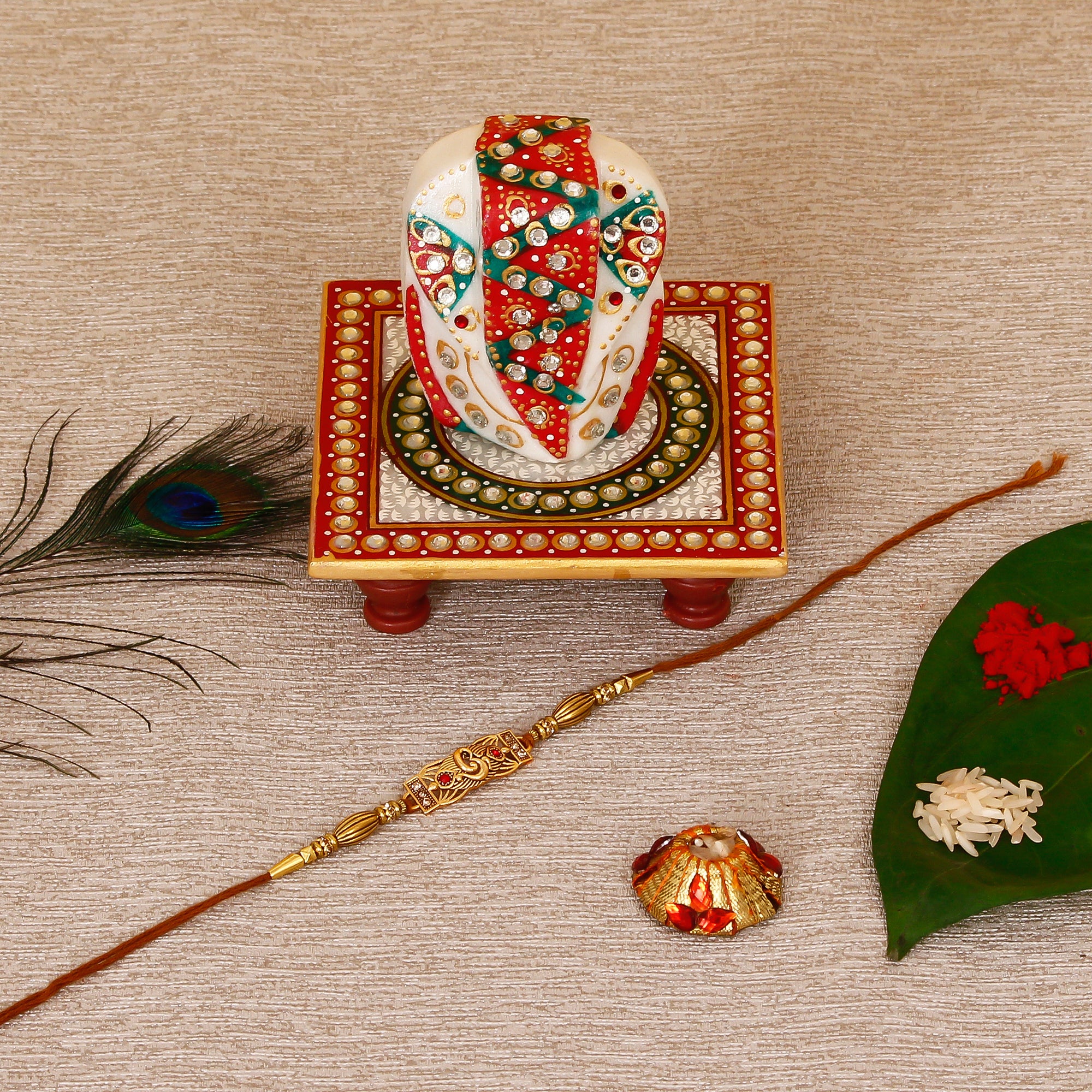 Designer Religious Rakhi with Lord Ganesha on Kundan Studded Marble Chowki and Roli Tikka Matki