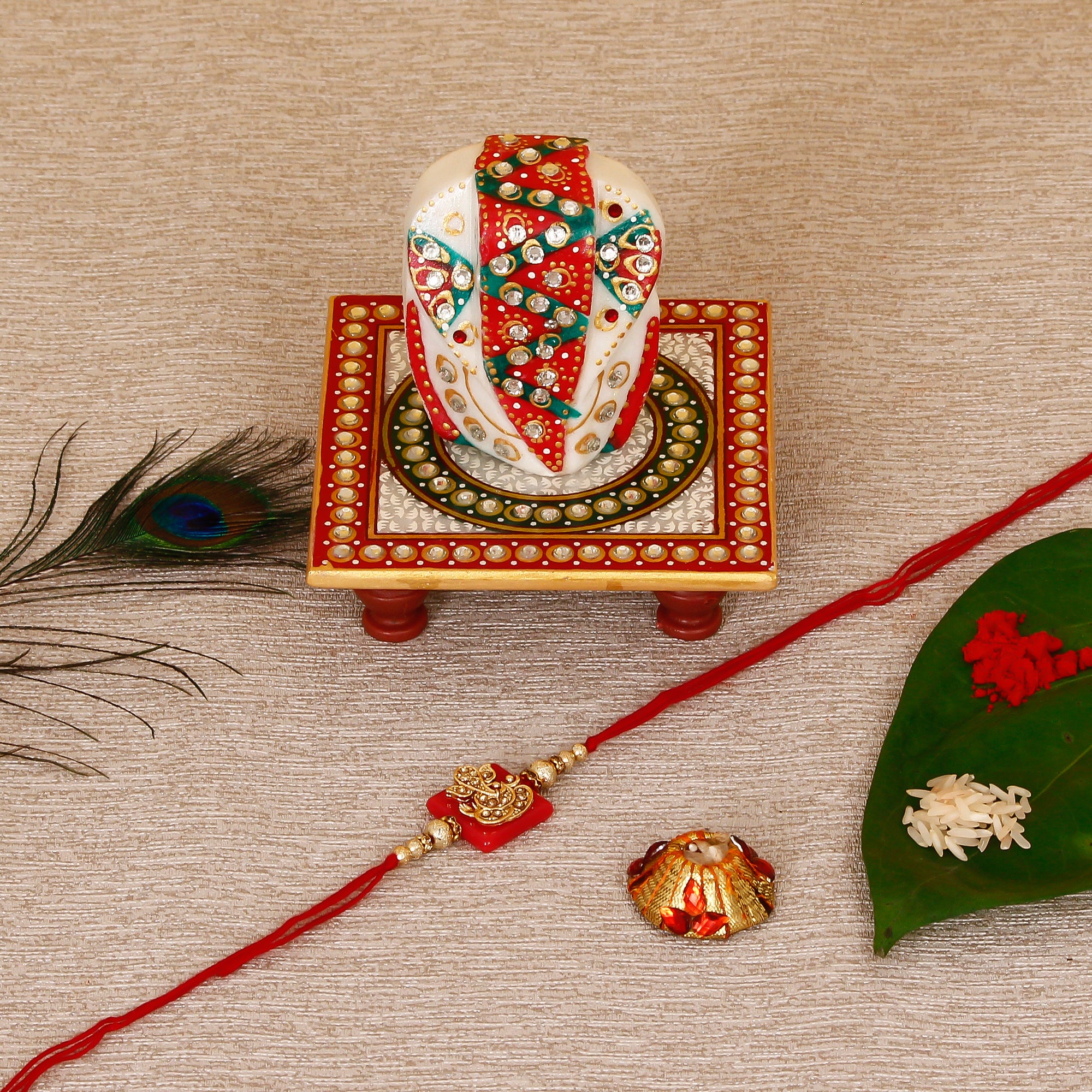 Designer Religious Ganesha Rakhi with Lord Ganesha on Kundan Studded Marble Chowki and Roli Tikka Matki